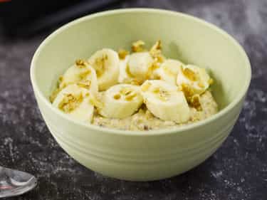 Photo of bowl of Growli Muesli with sliced banana, chopped walnuts, pinch cinnamon and spray cream