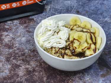 Photo of bowl of Growli Muesli with bananas, caramel syrup, spray cream and a little chocolate syrup