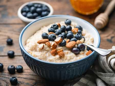 Photo of a bowl of porridge oats with blue berries and almonds