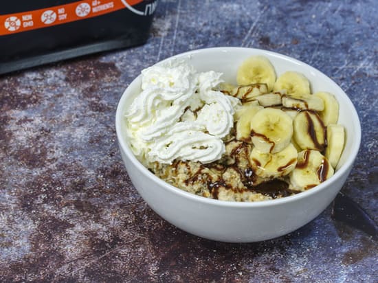 Photo of bowl of Growli Muesli with bananas, caramel syrup, spray cream and a little chocolate syrup