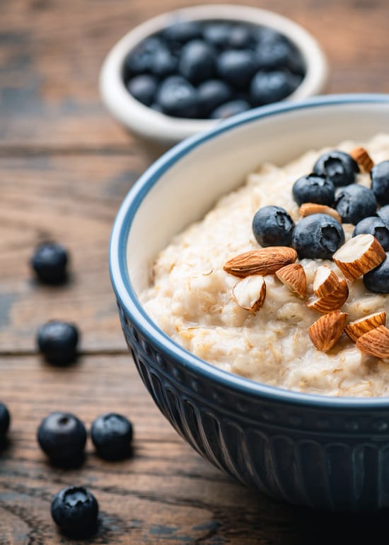 Photo of a bowl of porridge oats with blue berries and almonds